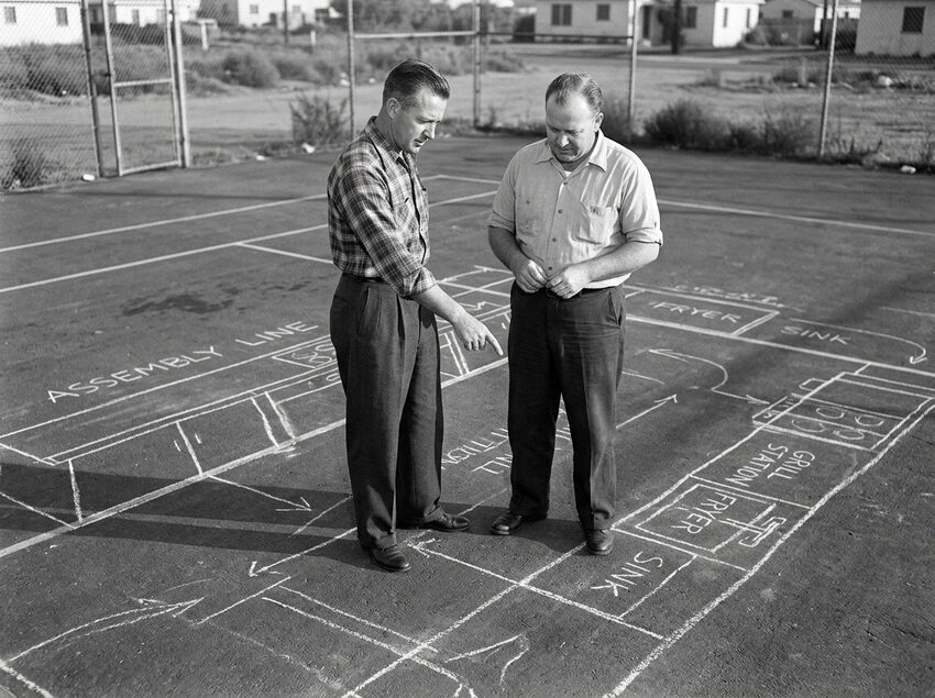The McDonald brothers mapping out kitchen assembly lines in chalk on an outdoor tennis court